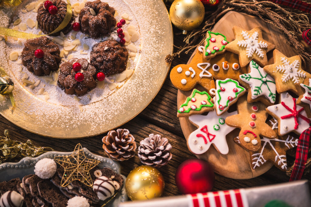 A variety of Christmas-themed cookies and desserts on a table, including gingerbread men, star-shaped cookies with icing, and chocolate treats.