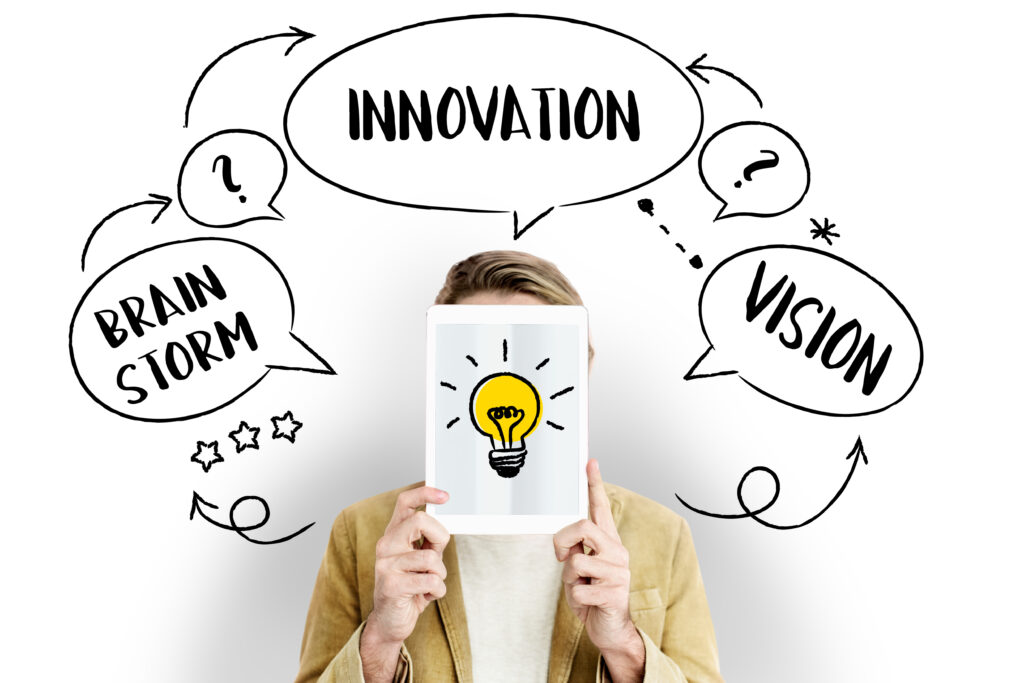 A person holding a tablet with a light bulb graphic, surrounded by hand-drawn words like "Innovation," "Brainstorm," and "Vision."