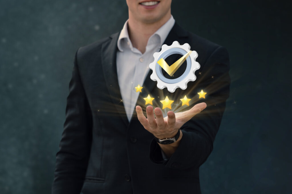 A man in a suit holding a graphic of a gear with a check mark and five stars.