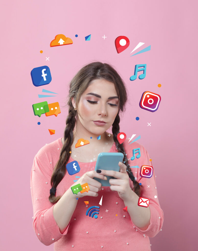 A young woman holding a smartphone surrounded by floating social media icons